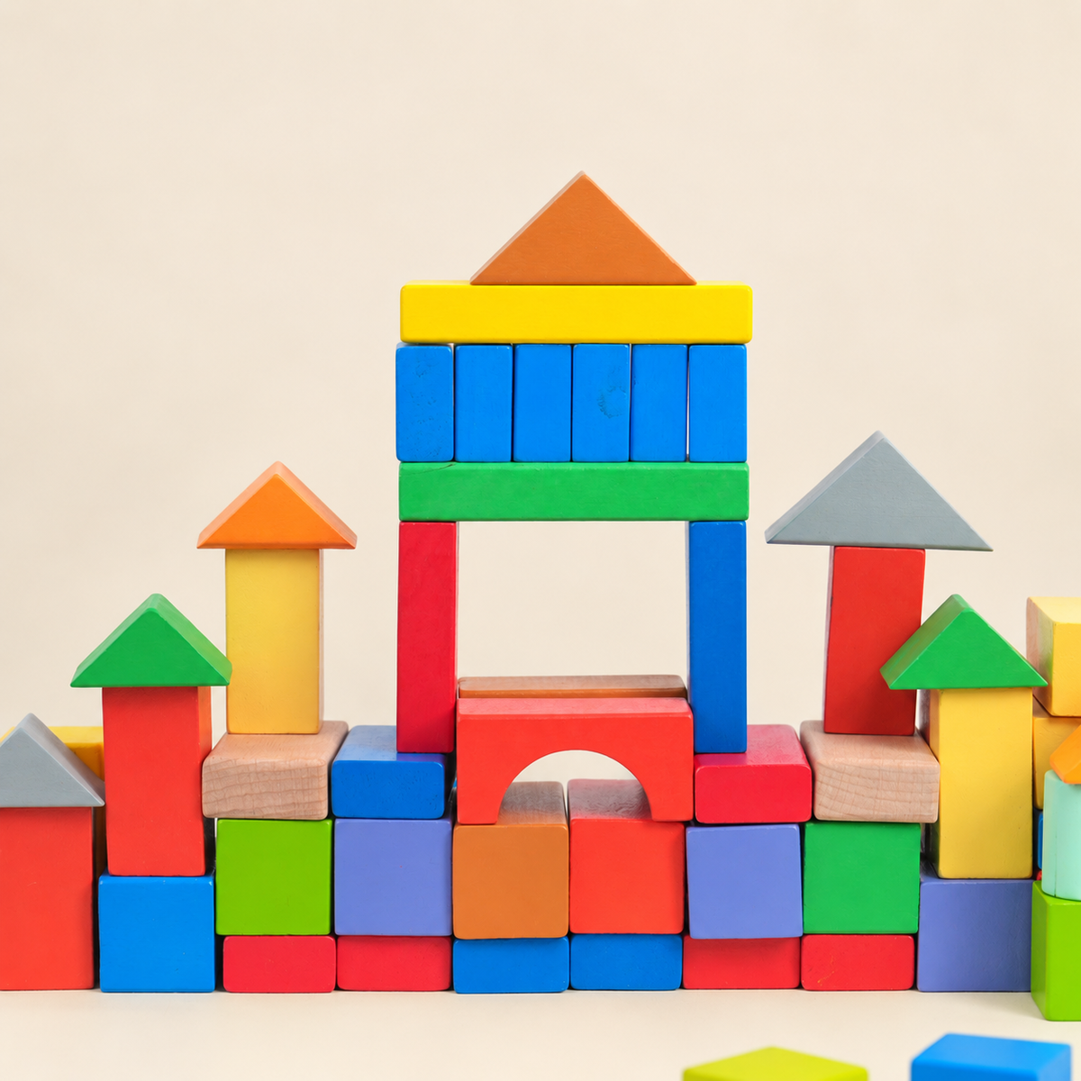 Colorful wooden blocks arranged in towers and arch on warm cream background